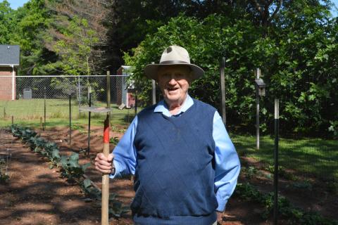 Drew Dotson/The Hartwell Sun - Milner poses with his trusty hoe in front of his backyard garden.