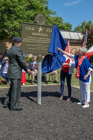 Pictured middle, from left to right, Col. G.T. Myers, Peggy Tucker and Sandra Brown unveil the Gold Star marker.