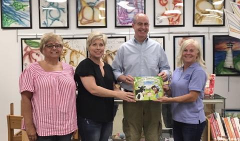 Submitted photo - Hart County Farm Bureau Women’s Committee chair, Patti York, right, Hart County Farm Bureau office manager, Tina Simmons, left, and Angie Brown, Hart EMC, present a copy of the children’s book “Tales of the Dairy Godmother: Chuck’s Ice Cream Wish” to Richard Sanders, who accepts the book for the Hart County Public Library. 