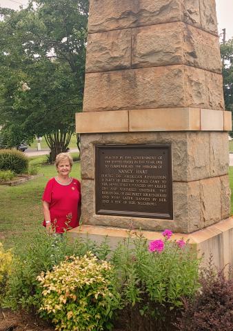 Dan Hunt/The Hartwell Sun Peggy Tucker poses next to the Nancy Hart monument near Old 29 Highway in Hartwell. Tucker helped to procure the monument and plant the adjacent garden. 