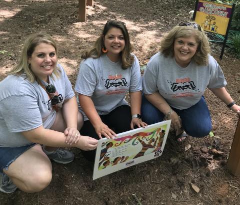 Submitted photo - Hartwell Elementary media specialist Erin Gaines, left, Andina Oglesby, middle, and South Hart media specialist Melissa Camp, right, install a story page along the path at the botanical gardens. 
