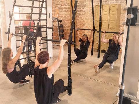 Physique Boutique employee (L-R) MattiGrace, Ashley Barry, Miyana Vaca and Lauren Lee demonstrate techniques on the gym's suspension bars.