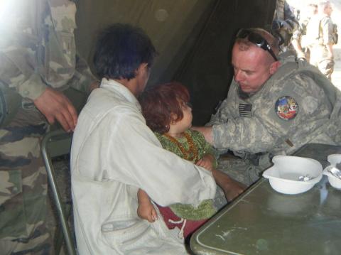 Jason Ford, currently Hartwell’s economic and community development director, treats a child overseas during his time as a medic for our armed forces. 