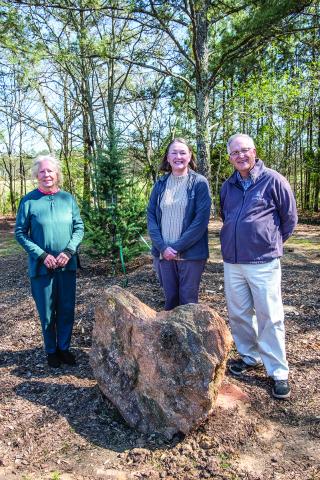 From left to right, Gretchen Torrence and Valerie and Bill Hinesley, stand near one of the new conifers and the heart-shaped rock along the conifer walk, The trio played large roles in the walk’s inception.