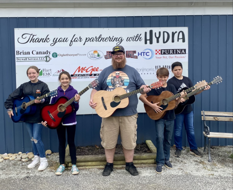 Kids learn guitar alongside their instructor at HYDRA event.