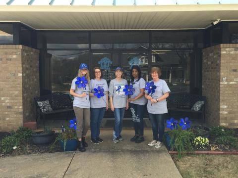From left to right, Andrea Ploussard, Wendy Risner, Laurie Whitworth (CEO), Kimberely Brewer and Sydney Jordan stand outside Harmony House holding blue pinwheels, which is the national symbol for child abuse prevention month. The pinwheel connotes playfulness, joy, and childhood. 
