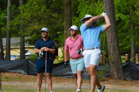 Pictured, John Daniel Gibbs tees off while his partner, Winston Gibbs (left), and Dillon Bowers (middle) watch the ball.