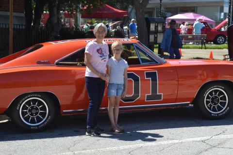 Dan Hunt/The Hartwell Sun - Sue Ackerman and her niece Emmeline Stith pose outside of the Post Office with a 1969 Dodge Charger made up to look like the famed General Lee from the Dukes of Hazzard. 