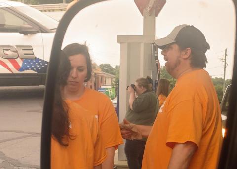 Dan Hunt/The Hartwell Sun Sideview mirror shot of three volunteers from The Pointe Church pumping gas and volunteering time and money in Lavonia on May 26. 