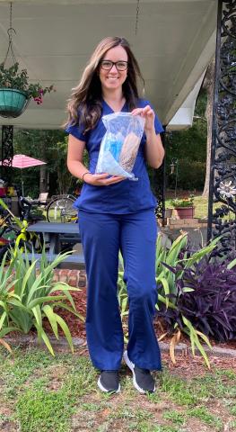 Nurse Cassie Gowder holds up her COVID protective gear she wore at work to help protect her patients. 