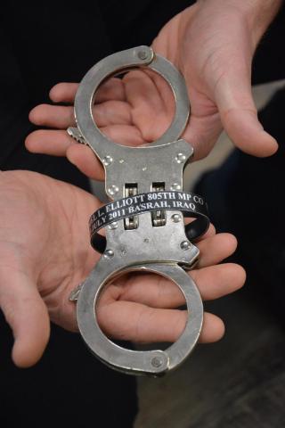 A pair of handcuffs owned by Jonathan Merck that were owned by a friend who was killed in Iraq were used to secure Gabrielle Beutler after she was arrested on charges of making up her veteran status and other charges. Merck wears a bracelet with the name of his friend, SPC Daniel Lucas Elliott. 