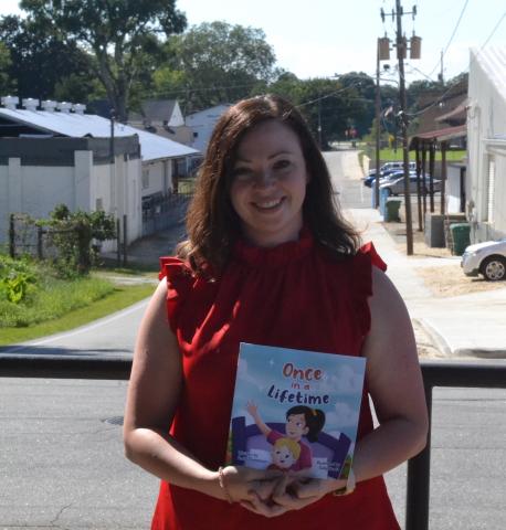 Emily Thompson holds a copy of "Once in a Lifetime," a children's book she authored in memory of her late best friend, Stevie Bruce.