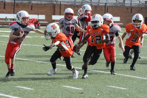 Hart County 7U running back Tristan Gray throws a stiff arm with defender Emmett Wise bearing down. 