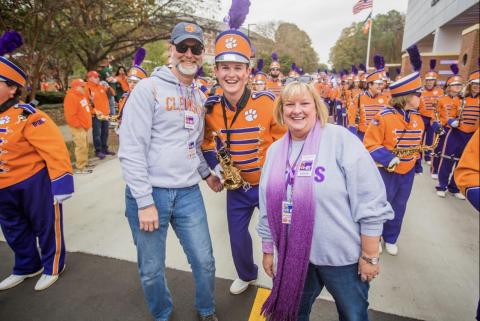 Dawson Baker, center, marches alongside his father Kevin Baker, left, and mother Lisa Baker, right, during Senior Day festivities at Clemson University before kickoff versus the University of Miami.