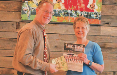 Enoch Autry, publisher for The Clayton Tribune in Rabun County, presents the $100 prize to Rabun County resident Melissa Elzey for winning the Spring 2023 Lake Living cover contest with her capture of the Lake Burton Ski Patriots’ performance on July 4, 2021.