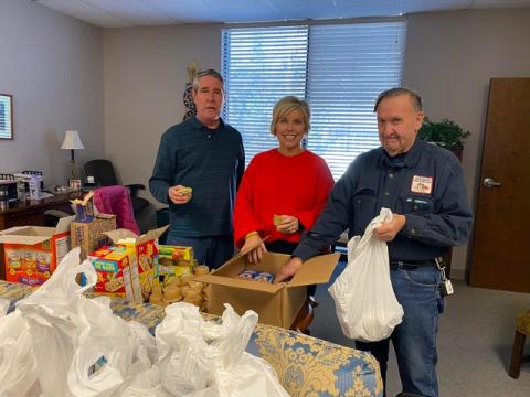 Hart EMC Director of Public Relations Angie Brown, center, recently visited the Hart Partners, Inc. offices in downtown Hartwell to see the Food for Kids Friday Backpack Program in action. Community volunteers Greg Blatt, left, and John Mead, add supplemental food items to bags.