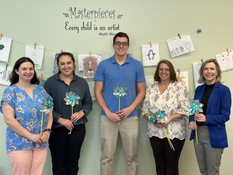 Several members of Harmony House’s team holding blue pinwheels, a reminder of National Child Abuse Prevention Month. Left to right: Kaitlin Andrews, child and family services advocate; Olivia Owensby, director of forensic services; Darrin Haley, clinical director; Wendy Risner, outreach/volunteer coordinator; and Laurie Whitworth, CEO. 