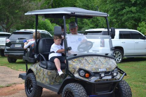 Jackson Moon and his father Zachary riding in their brand new golf cart from the Make-A-Wish Foundation. 