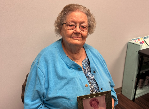 Frances Bailey holding an older photo of herself.