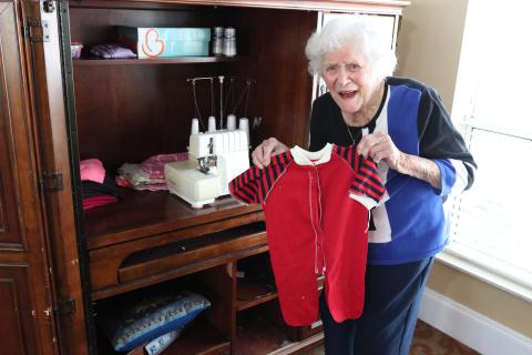 Doris Mahannah, 108, presents a handmade onesie before the finishing touches are added. She sews baby clothes for Tiny Stitches, a nonprofit that provides handmade sewn and knitted items to newborns in need across north Georgia. (Photo/Adriana Cascio)