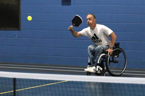Phillip Henderson, 51, strikes a pickleball while maneuvering his wheelchair at the YMCA on Monday. Henderson, paralyzed at 14, has played sports his entire life and continues to exercise almost daily. (Photo/Adriana Cascio)