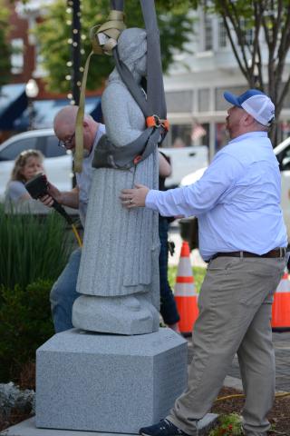 Hartwell Economic and Community Development Director Jason Ford (right) helps hold the statue in place as Mart Clamp helps adhere the statue to its pedestal (left). (Photo/Benjamin London)