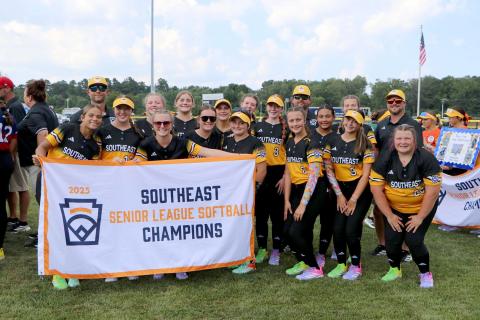 Hart County Senior League Softball team poses with their Southeast Champions banner before a game in the Senior League Softball World Series in Lower Sussex, Delaware. The team consists of Milo Allen, Marlee Bowers, Maggie Bridges, Ky Dubose, Kinsley Duncan, Peyton Jordan, Emory McCollum, Peyton McCollum, Emma Mitchell, Kam Price, Erika Royston, Bella Segars, Chesnee Strickland, EmmaKate White and MaryBeth White. The team is coached by Kyle McCollum, Mason Bowers, Tony Strickland and Head Coach Paul Mitchel