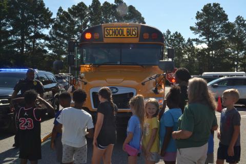 Hartwell Police Department Lt. Darin Rucker shows off a Hart County Charter System bus’s safety features to children at the Bell Family YMCA, located at 281 Opal Ext., on Tuesday. All buses are equipped with flashing lights, a stop sign and a crossing arm to ensure the safety of students entering and exiting the vehicle. (Photo/Adriana Cascio)