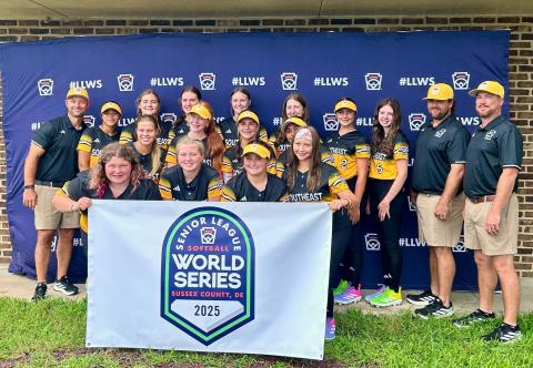 Hart County Senior League Softball team poses with a Senior League World Series banner before a game in the Senior League Softball World Series in Lower Sussex, Delaware. (Photo courtesy of Hart County Little League)