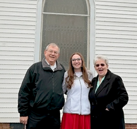 Redwine church members Barry (left) and Theresa Summey (right) pose with their granddaughter, Olivia Summey (center), in front of the new stained glass window Barry completed for the church. Barry credited Olivia for doing the lettering, which features the name of the church, under the cross. Photo submitted by Barry Summey.