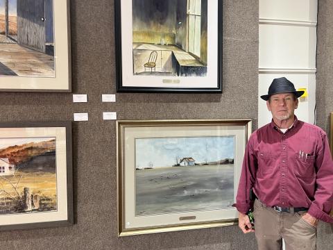 Stan O’Bannon stands next to his works at the Hartwell Art Center. His exhibit will kick off with an opening reception tonight and will be open through March 21. Photo by Madison Linton.