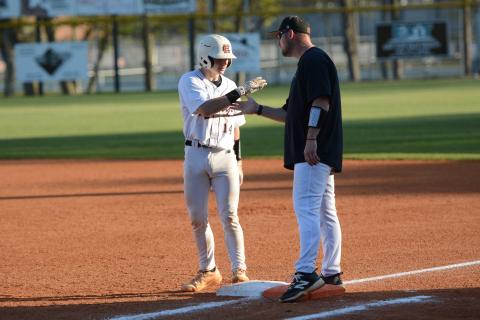 Sophomore catcher Slate Osborne celebrates with first base coach Chris Wilson after pushing across two runs in the 15-2 loss to Franklin County March 23. Photo by Benjamin London. 