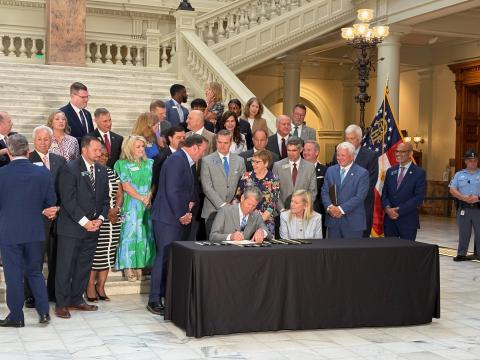 Gov. Brian Kemp selects a pen to sign tax legislation at the Georgia Capitol in Atlanta on Monday, with wife Marty by his side. House Speaker Jon Burns, R-Newington, watches to her left. Photo by Ty Tagami.