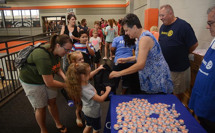Hartwell Rotary Club member Ganine Derleth gives hand sanitizer to Elektra Head, 7, and her sister Ziva Head, 5, while their mother Kimberly Head helps and club member Mike Everett, standing at right, looks on.