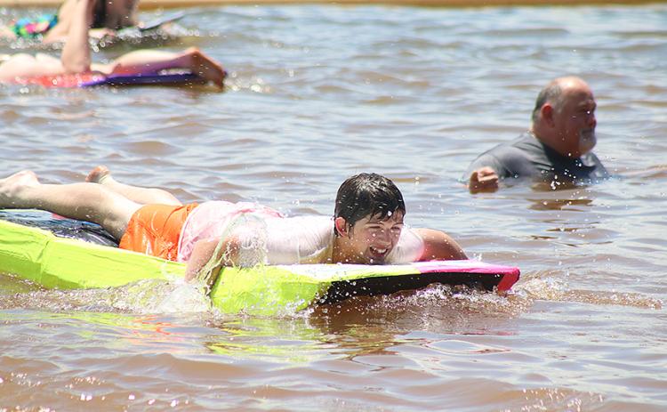 Sunshots by Grayson Williams — Carter Reed navigates his paddle-board style boat past band director Alan Tolbert, right, who officiated the event from the water.