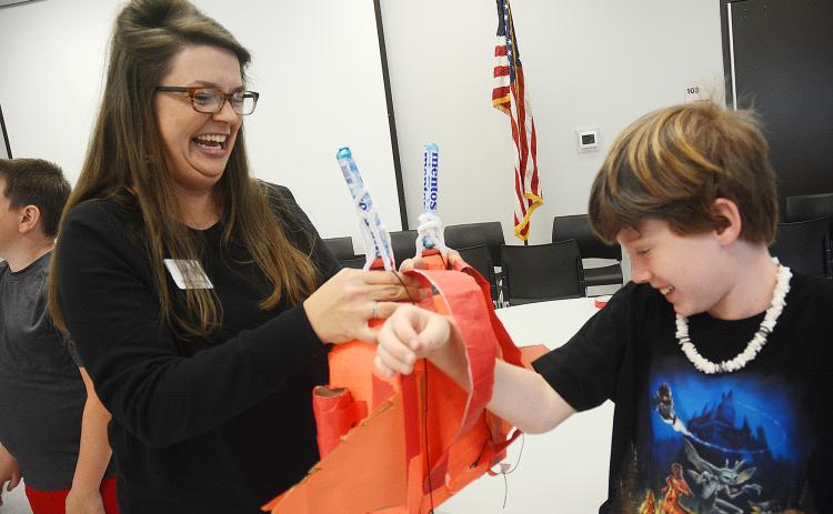 Sunshot by Michael Hall — North Hart Elementary School Teacher of the Year Emilee Patrick helps Ryan Belanger put a jetpack he invented on his back during the recent Invention Convention at the Agriscience Center.