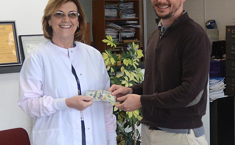 Elaine Jones, left, receives her $100 reward for winning the Lake Living winter cover contest from The Hartwell Sun publisher Michael Hall.