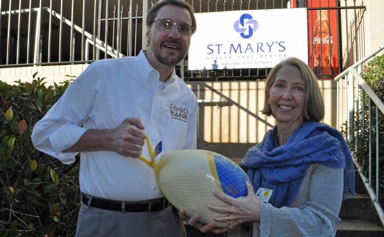 Photo submitted — Food Bank of Northeast Georgia Executive Director Chuck Toney, left, accepts a turkey from St. Mary’s Vice President of Mission Services Julie Carter.