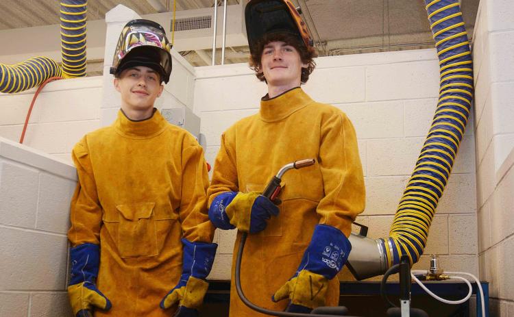 Sunshot by Michael Hall — Hart College and Career Academy students Zack Hart, left, and Austin Brown, right, pose for a photo in the welding lab at the school recently.  The pair were hired recently to work at Fabritex in Hartwell.