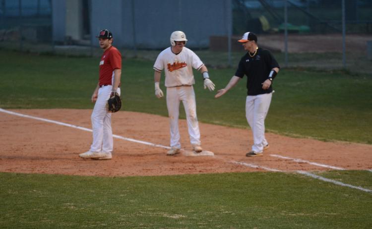 Luke Lee, left, is congratulated by coach Hunter Barton, at first base after Lee’s line drive that drove in a run to take the lead against Morgan County on Monday at Saye Field.