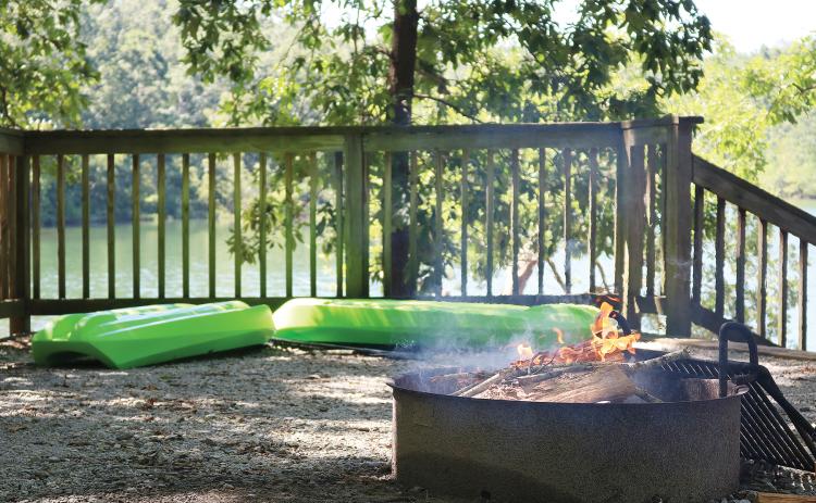Sunshot by Grayson Williams — A fire burns in a fire pit as kayaks wait to hit the water at a Hartwell Lakeside campsite recently.