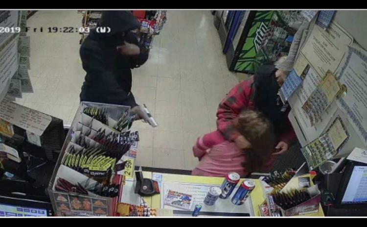 Photo submitted — This image taken from surveillance footage and posted on social media by Parks White shows a man pointing a pistol at a young girl during an armed robbery at a local Jimbo’s convenience store on Dec. 6, 2019.