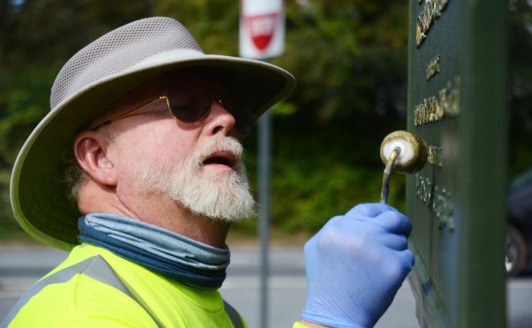 Tom Stelling carefully dabs gold paint on the lettering of the Blue Star Memorial at the corner of Athens and Howell streets in Hartwell on Oct. 25.