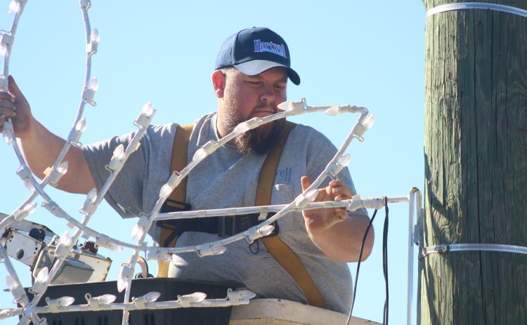 Justin Saylors fixes a lighted snowflake to a utility pole on Depot Street Tuesday afternoon.
