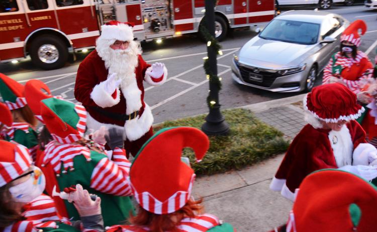 Santa waves to his elves as they greet him and Mrs. Claus, who hitched a ride to the event with the Hartwell Fire Department.