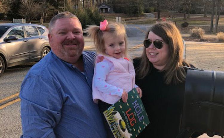 Charlie and Kim Pierce pose for a picture with their daughter, Camille, and a book provided by the Imagination Library.  Photo submitted