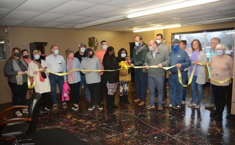 Owner Natasha Fields, pictured in the center with the scissors, is joined by her daughter Taryn Fields, to her left, fiance Daryl Denney, behind her, and her mother, Thelma Bowens, as well as members of the Hart County Chamber of Commerce board of directors, Mayor Brandon Johnson, councilman Tray Hicks, and members of Hartwell Main Street and the Downtown Development Authority.