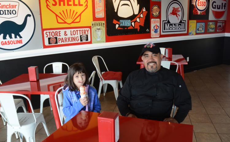 Omar Vega, right, and his daughter, Anna Blazek, left, sit in the newly remodeled Scoops by Rolling Chefs.