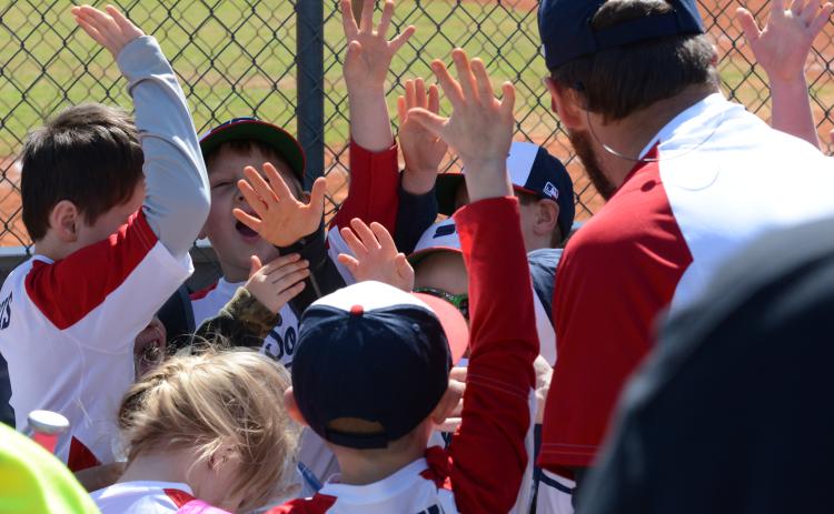 The “Sox” tee-ball team triumphantly break a huddle after their game.