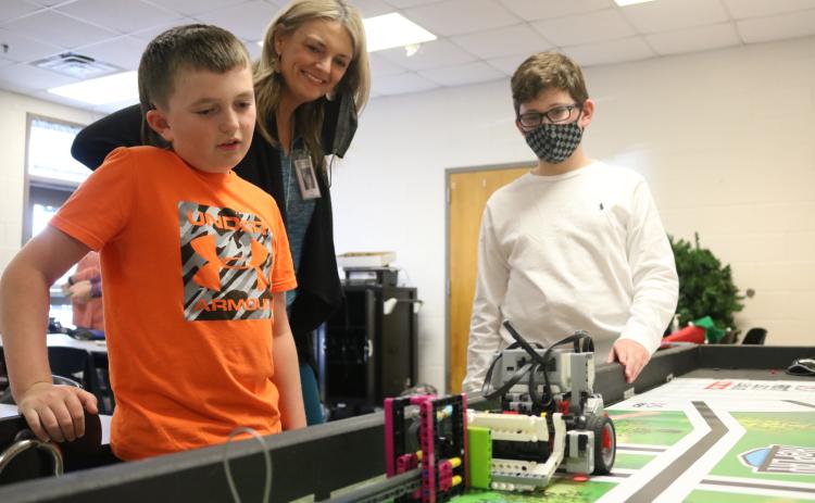 Grayson Williams/The Hartwell Sun South Hart Mindtwister team members Easton Kelley, left, and River Powell, right, eye their robot named “Robie” as it performs a task  and coach Tonya Bridges, center, watches on Thursday, April 22 at South Hart Elementary School.